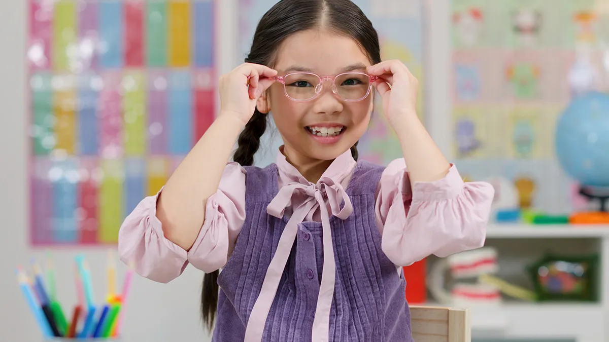 A young girl wearing glasses in a classroom
