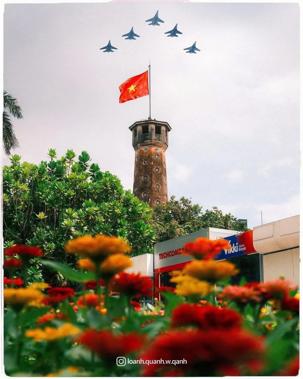 Hanoi Flag Tower beyond a flower garden